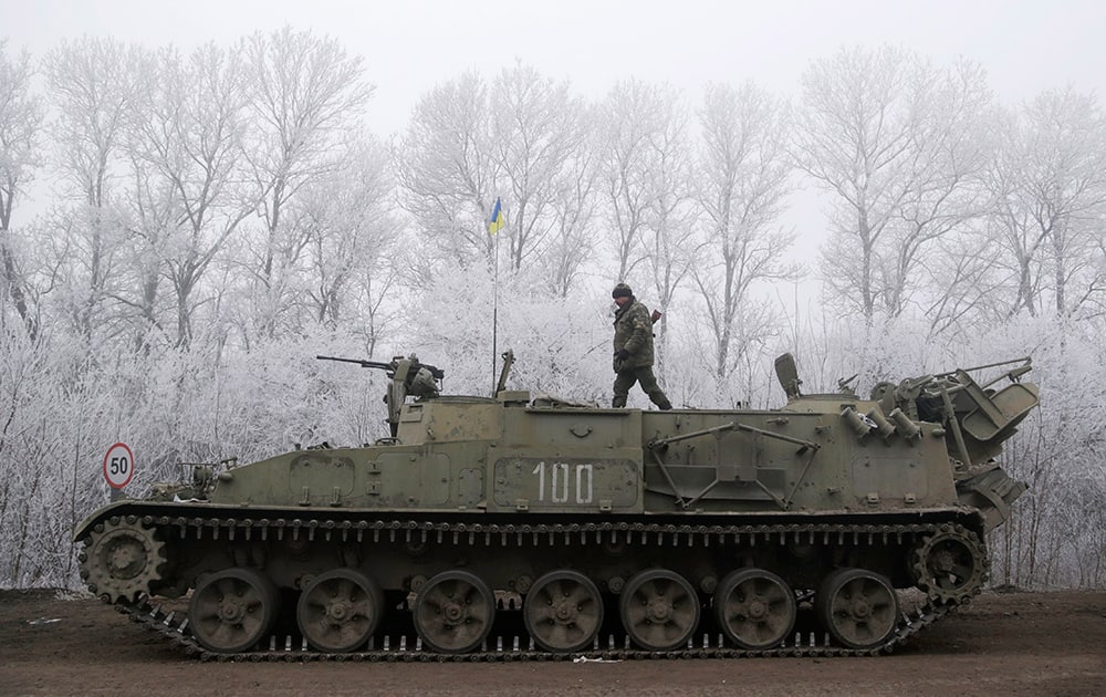 Ukrainian government soldier walks atop of his armored vehicle on the road between the towns of Dabeltseve and Artemivsk, Ukraine.