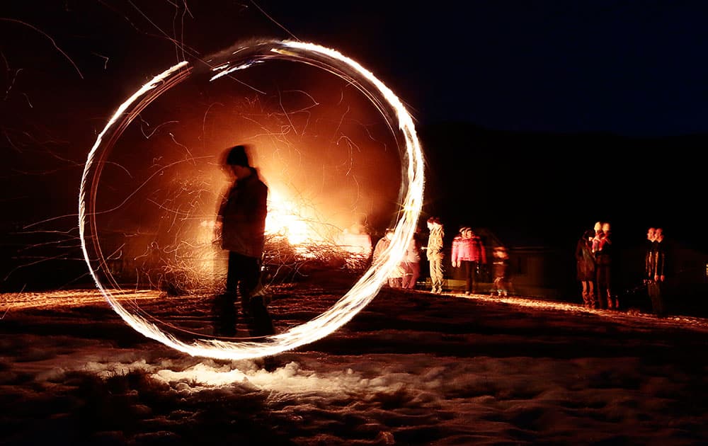 This photo taken with a long exposure photo, a silhouetted child spins a ball of fire during rituals in celebration of Mesni Zagovezni (Shrovetide) in the village of Lozen near the capital Sofia.