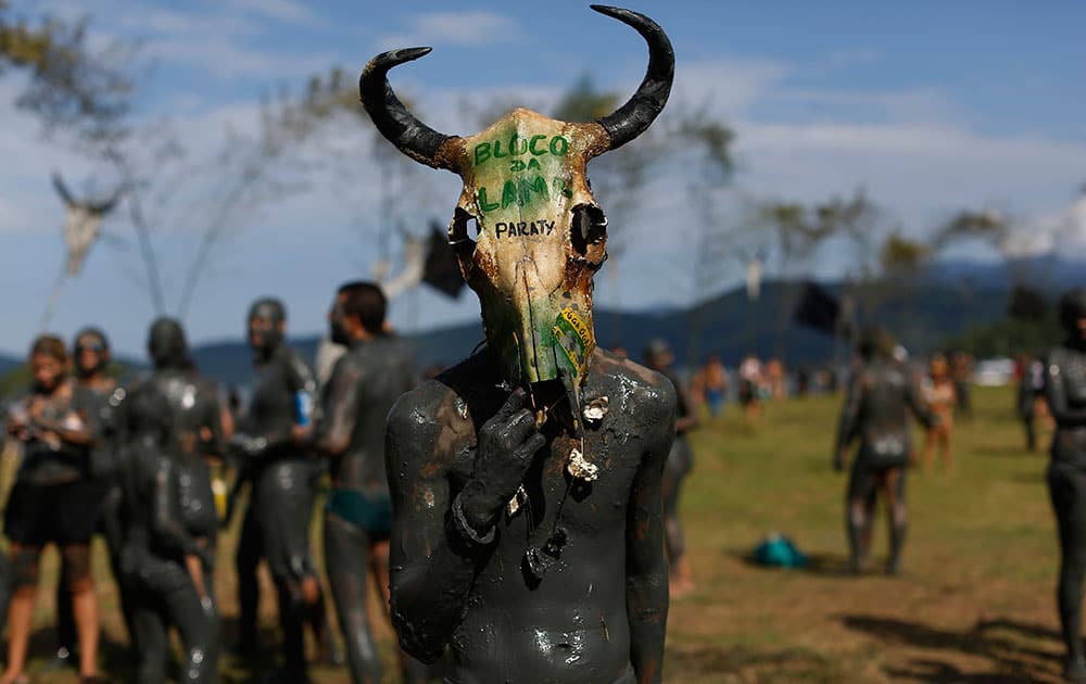 A mud covered reveler wearing a cow's skull as a mask poses for a photo during the traditional 'Bloco da Lama' or 'Mud Block' carnival party, in Paraty, Brazil.