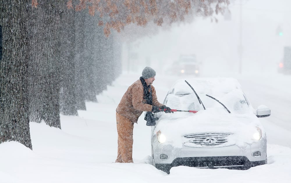 Daniel Mattingly cleans the snow off his car, which had accumulated while he was at work in Lexington, Ky.