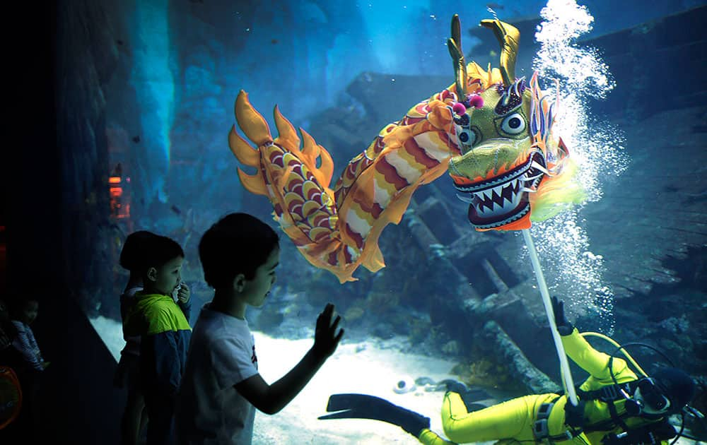 Children watch as divers perform a dragon dance underwater at the South East Asia Aquarium in Resorts World Sentosa, a popular tourist destination, as part of Chinese New Year celebrations, in Singapore. 