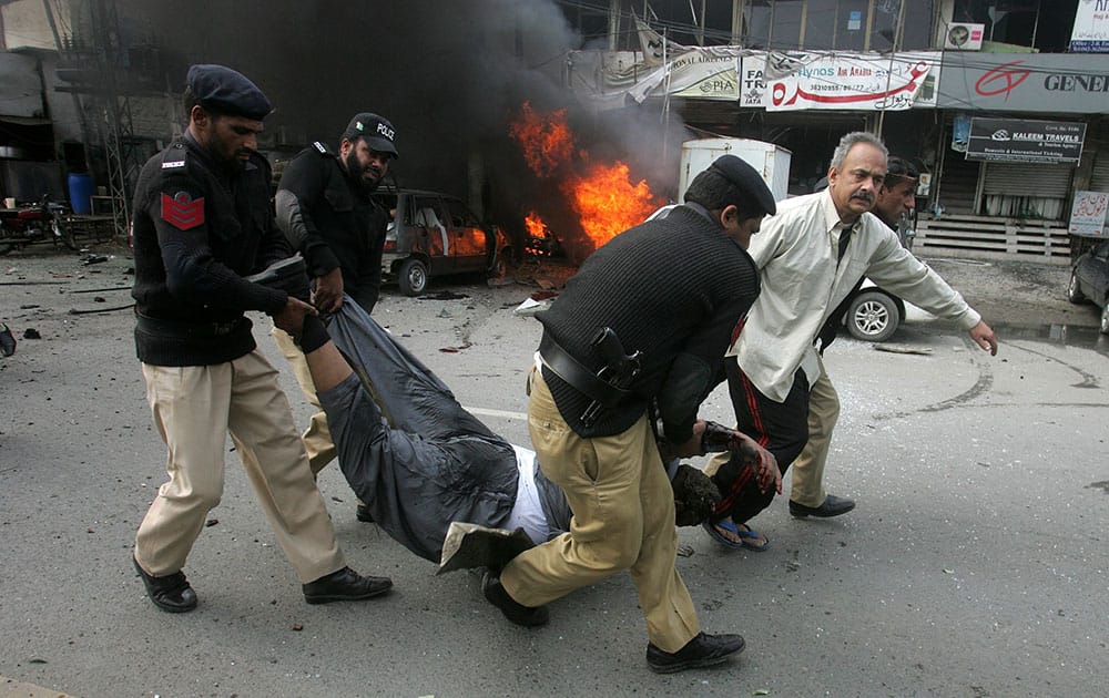 Pakistani police officers and a volunteer rush an injured person to a hospital after a bombing in Lahore, Pakistan.