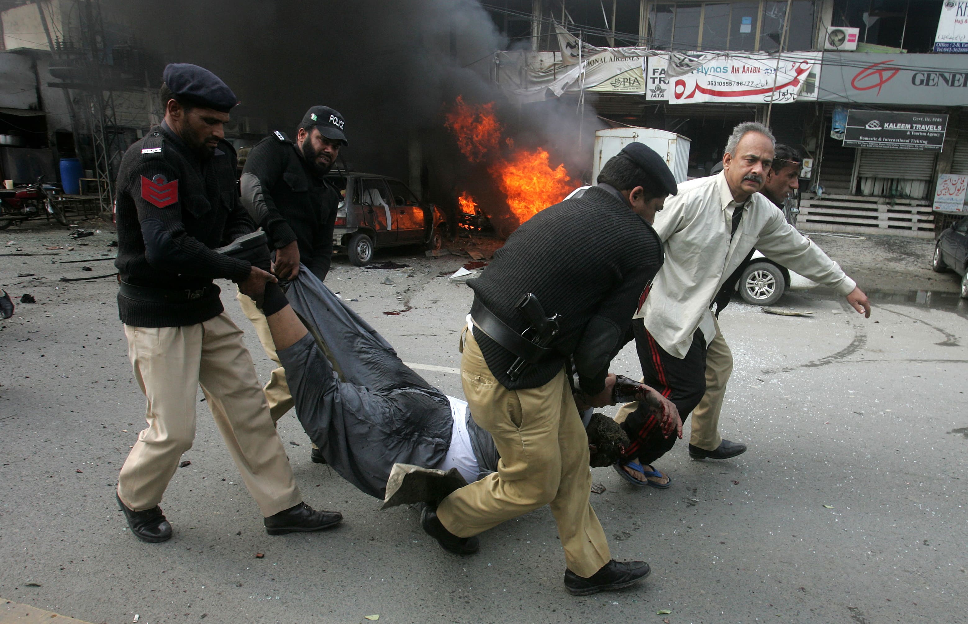 Pakistani police officers and a volunteer rush an injured person to a hospital after a bombing in Lahore, Pakistan.