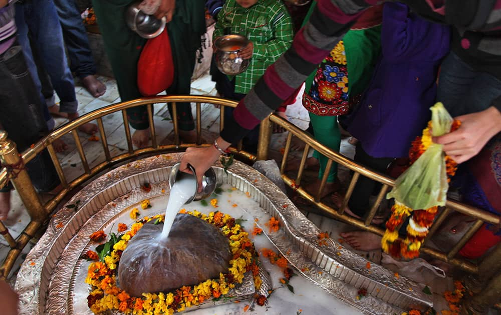 Devotees pour milk on a Shivling, an idol symbolic of Hindu god Shiva, at the Aap Shambhu Lord Shiva temple during 