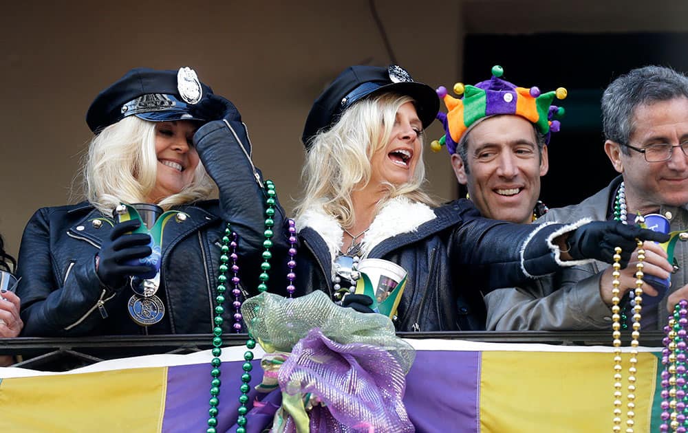 Revelers throw beads from a balcony during Mardi Gras day festivities on Bourbon St. in the French Quarter of New Orleans.