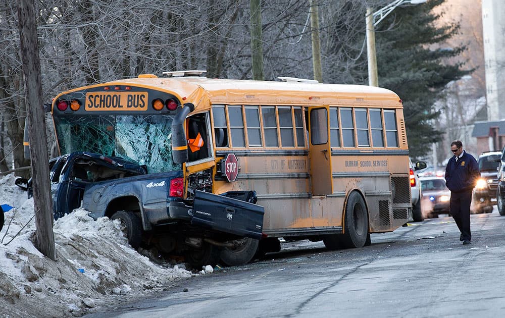 Waterbury police investigate the scene where a school bus and truck collided in Waterbury, Conn. Police say two people in a pickup have died after colliding head-on with the school bus that wasn't carrying any children.