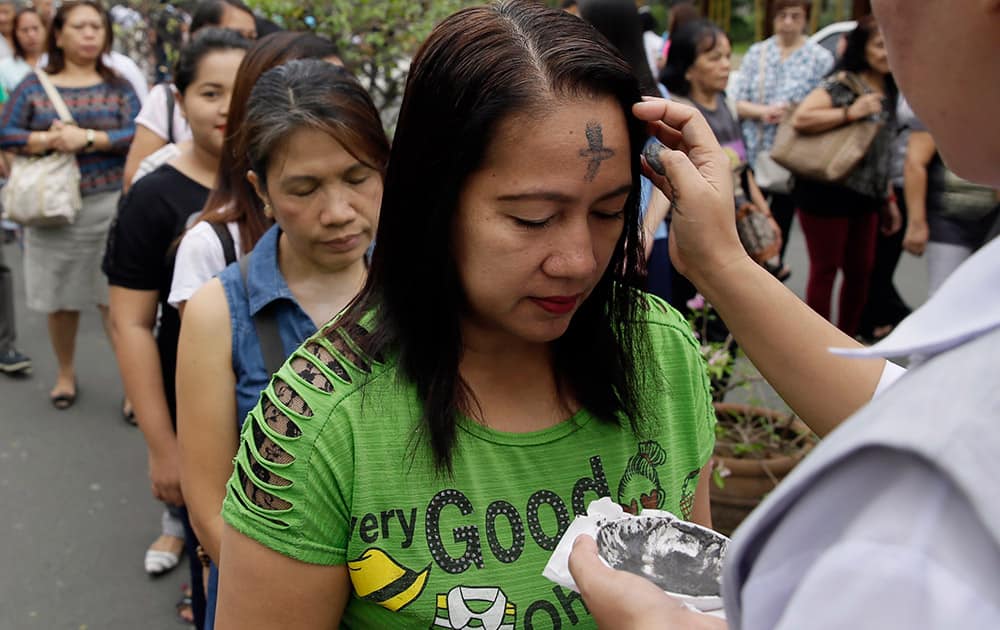 A Catholic nun uses an ash to mark with a cross the foreheads of devotees in observance of Ash Wednesday among Roman Catholics at The Redemptorist Church at suburban Paranaque city, south of Manila, Philippines.