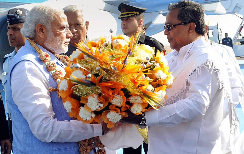 Prime Minister Narendra Modi being received by the Chief Minister of Karnataka Siddaramaiah on his arrival at the airport in Bengaluru.