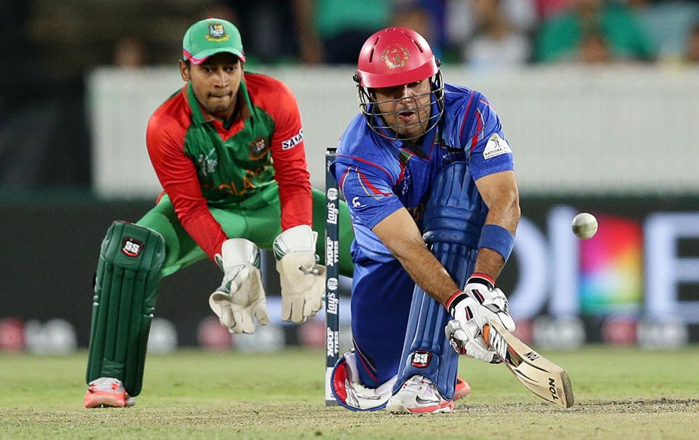 Afghanistan batsman Mohammad Nabi plays a sweep shot as Bangladesh wicketkeeper Mushfiqur Rahim looks on during their Cricket World Cup Pool A match in Canberra, Australia.