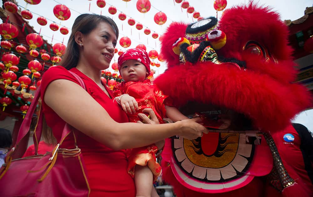 A Malaysian ethnic Chinese woman and her child poses for their souvenir photo with the lion dance on the first day of Chinese Lunar New Year at a temple in Kuala Lumpur, Malaysia.