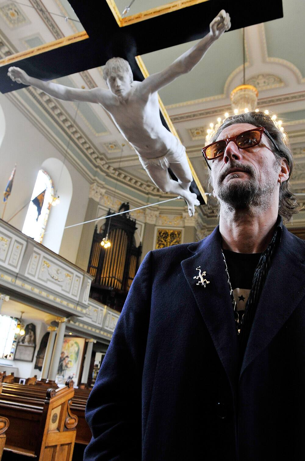 Artist Nick Reynolds stands beneath his life size crucifixion sculpture of Pete Doherty entitled 'For Pete's Sake', made in 2008 as a collaboration between him and Pete Doherty, as it hangs alongside other works that make reference to the Passion of Christ as part of the Stations of the Cross exhibition, at the 200 year old St. Marylebone Parish Church, London.