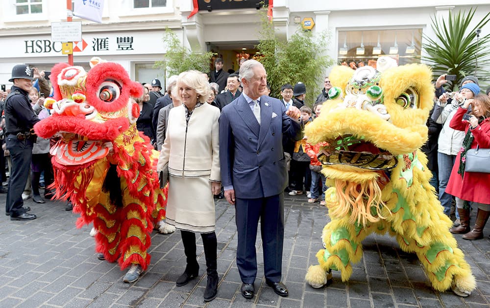 Britain's Prince Charles and Camilla, Duchess of Cornwall pose with a dragon and lion dancers, during an official visit to Chinatown to mark Chinese New Year, in Chinatown, in London.