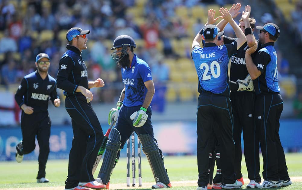 England's Moeen Ali, centre, walks from the field as New Zealand players celebrate his dismissal during their Cricket World Cup match in Wellington, New Zealand.