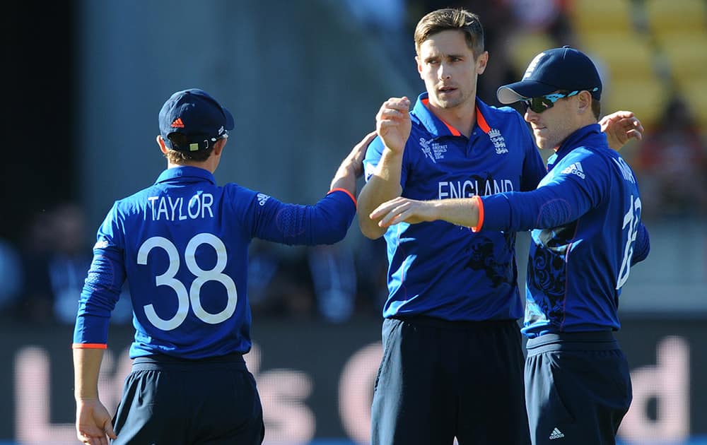 England's Chris Woakes, centre, is congratulated by teammate James Taylor and his captain Eoin Morgan, right, after dismissing New Zealand batsman Martin Guptill during their Cricket World Cup match in Wellington, New Zealand.