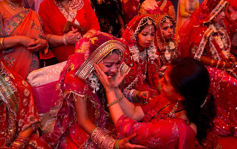 A relative cheers a bride as she sits with other Indian brides from impoverished families, waiting for their grooms to arrive during a mass marriage ceremony in New Delhi.