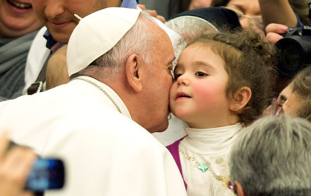 Pope Francis kisses a baby as he arrives for a special audience with members of the dioceses of Cassano allo Jonio, southern Italy, at the Vatican.