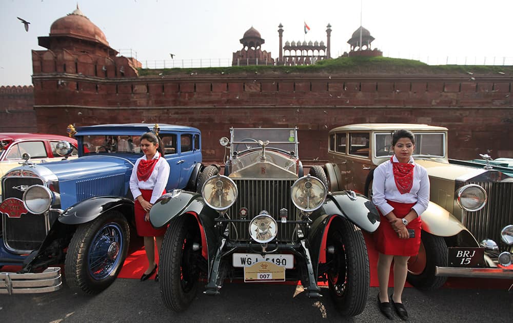 Promotional models stand by vintage cars during the 21 Gun Salute International Vintage Car Rally in front of the historic Red Fort monument in New Delhi.