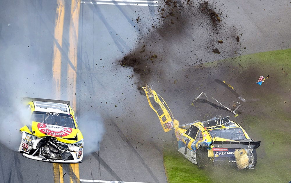 Regan Smith (7) lands on the infield grass after flipping on the front stretch after being involved in a multi-car accident, as Jeff Green (10) drives past, during a NASCAR Xfinity series auto race at Daytona International Speedway.