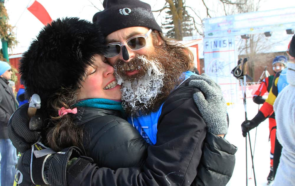 Scott Scheirbeck, of Duluth, Minn., with part of his beard coated in ice, gets a kiss and a hug from his wife, Nancy Meisinger, after he finished the American Birkebeiner cross-country ski race in Hayward, Wis.