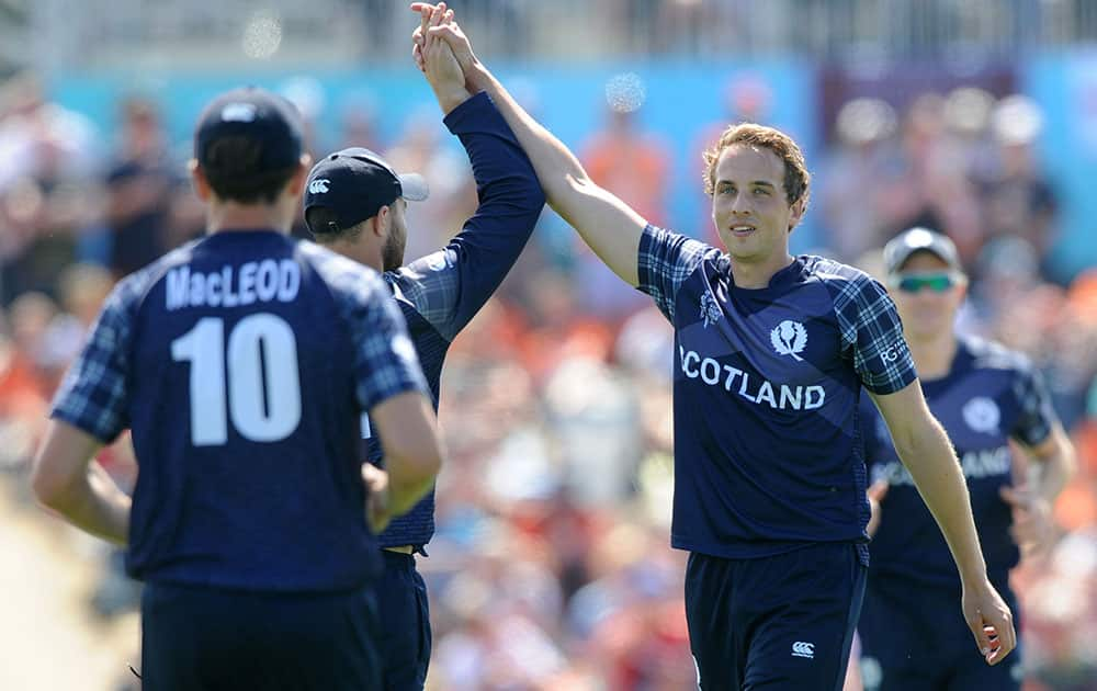 Scotland's Josh Davey, right, is congratulated by teammates after taking a wicket during their Cricket World Cup match against England in Christchurch, New Zealand.