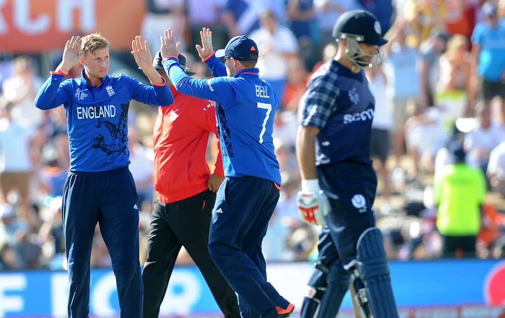 England's Joe Root, left, is congratulated by teammate Ian Bell after dismissing Scotland's Preston Mommsen, right, during their Cricket World Cup match in Christchurch, New Zealand.