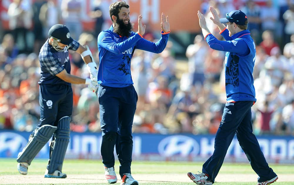 England's Moeen Ali centre, is congratulated by his captain Eoin Morgan after taking the wicket of Scotland's Richie Berrington, left, during their Cricket World Cup match in Christchurch, New Zealand.