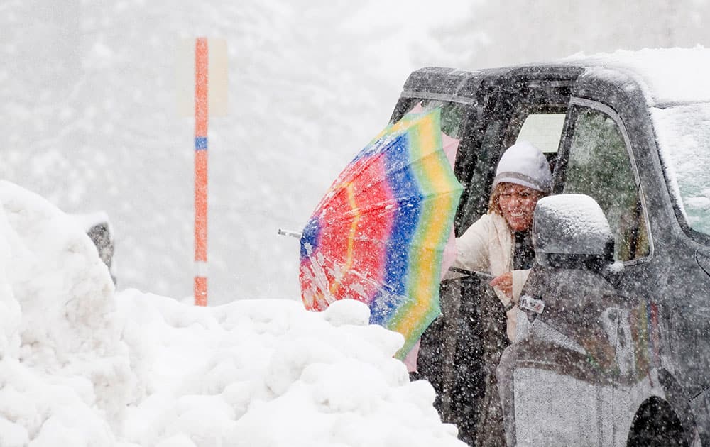 Carmen Lopez, of Palmdale, Calif., shakes snow from her umbrella, in Wrightwood, Calif.