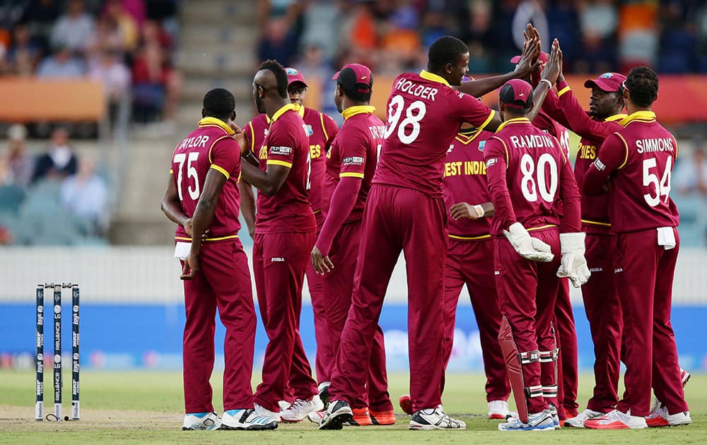 West Indies team celebrate after the dismissal of Zimbabwe's Regis Chakabva during their Cricket World Cup Pool B match in Canberra, Australia.