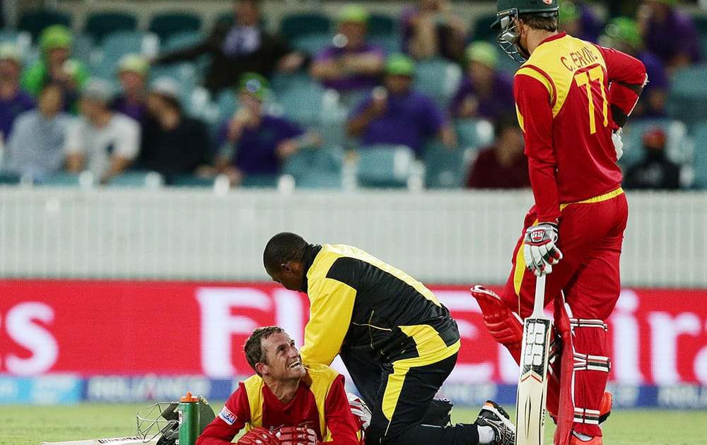 Zimbabwe's Sean Williams receives treatment from a trainer as teammate Craig Ervine watches during their Cricket World Cup Pool B match against the West Indies in Canberra, Australia.