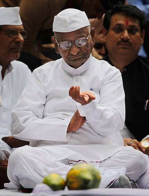 Anna Hazare looks at his watch as he sits on a stage during a protest against the government’s proposed move to ease rules for acquiring land to facilitate infrastructure projects in New Delhi.