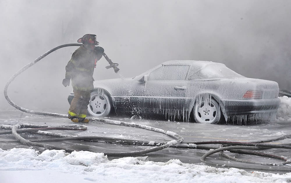 A Detroit fireman from Engine 41 continues to douse the hot embers from an overnight fire at an inhabited building in Detroit.