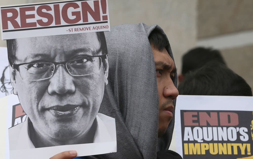 A protester displays a placard with an image of President Benigno Aquino III as they march towards the People Power Monument, calling for the resignation of Aquino at suburban Quezon city, Philippines, to coincide with the 29th celebration of the 