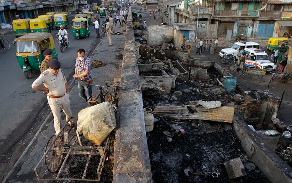 A police officer looks at the debris of a slum area from a road after it caught fire in Ahmadabad.