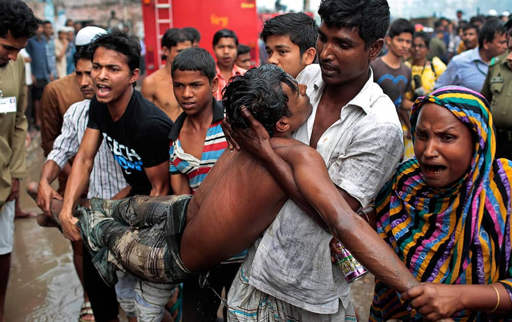 A Bangladeshi man who fainted after seeing the body of his child who died in a slum fire is carried by others in Dhaka, Bangladesh. About 50 shanties were gutted down in the fire.