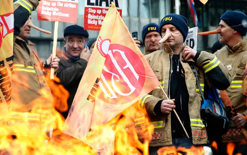 Members of the Fire Brigade Union huddle round a fire as they take part in a demonstration as they hold a 24 hour national strike over pensions in London.