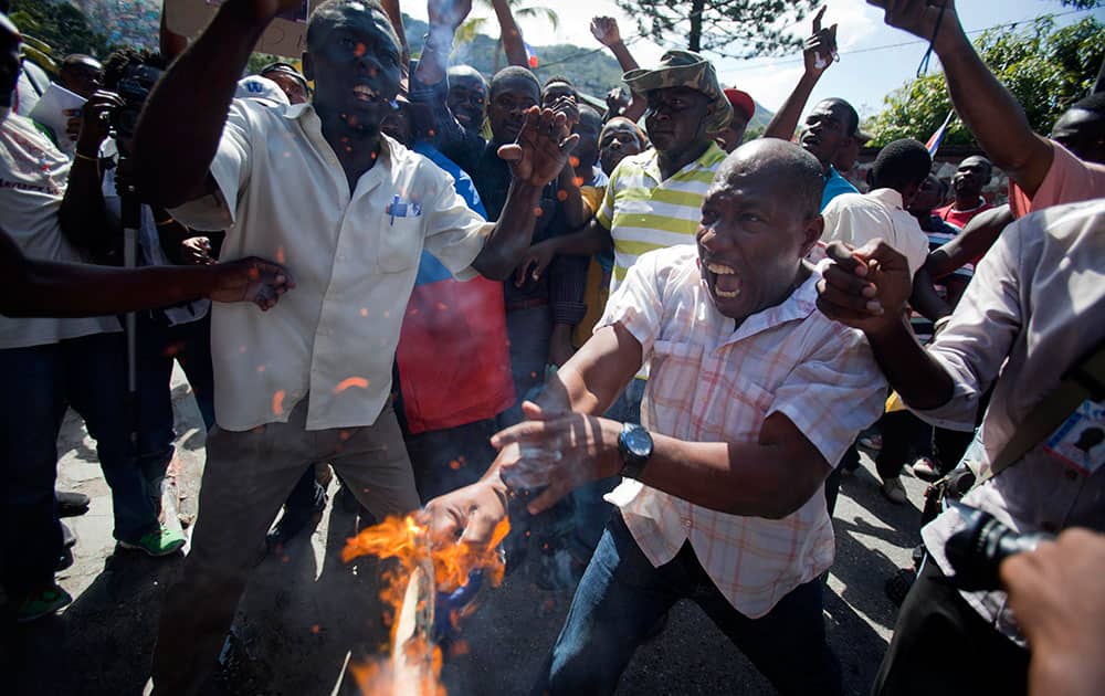A man yells out in pain as his hand catches fire from a burning Dominican national flag he was holding, during an anti-Dominican Republic protest, in front of the country's consulate in Port-au-Prince, Haiti.