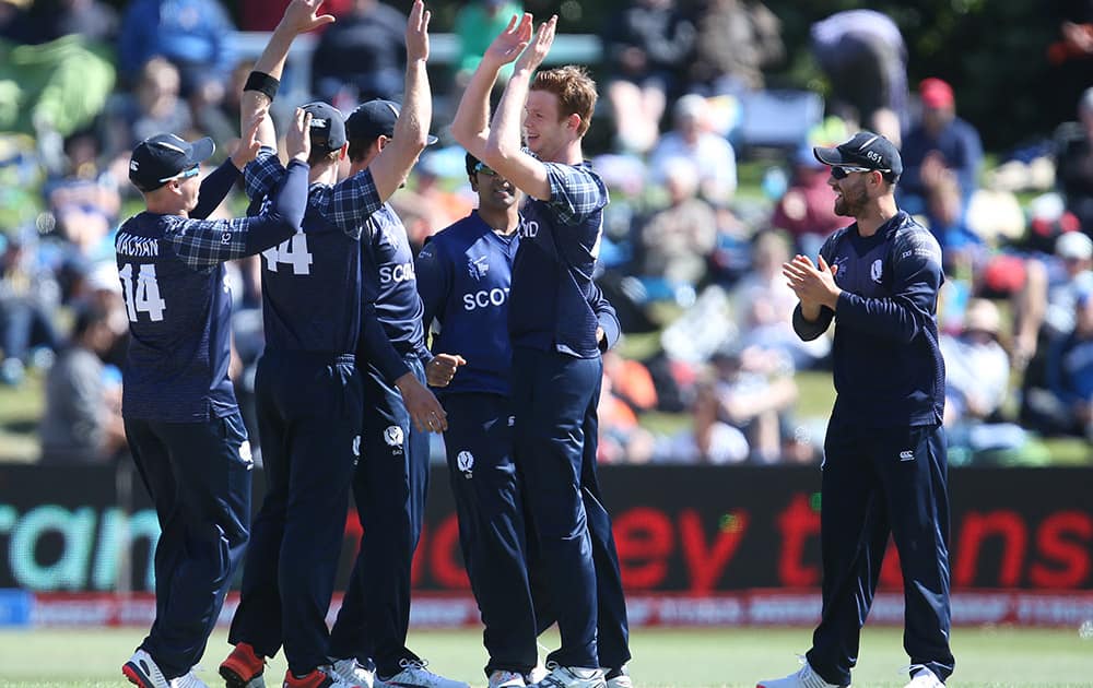 Scotland's Ali Evans, is congratulated by teammates after taking the wicket of Afghanistan's Nawroz Mangal during their Cricket World Cup Pool A match in Dunedin, New Zealand.