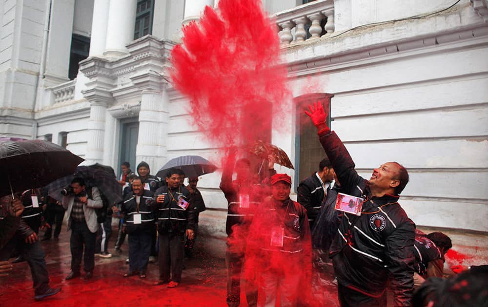 A Nepalese devotee throws vermillion powder after erecting Chir, a ceremonial pole, marking the beginning of Hindu festival of colors Holi, in Kathmandu, Nepal.