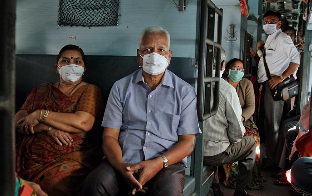 Passengers wear a protective mask as they sit in a train compartment in Ahmedabad. Officials prohibited gatherings of five or more people in Ahmedabad, the capital of Gujarat state, in an attempt to halt the spread of swine flu, starting Wednesday. Marriages and funerals are exempt from the ban, but participants will need to wear protective masks, officials said.