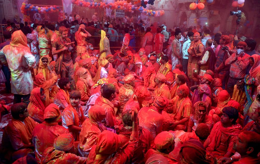 Devotees covered in coloured powder, as they celebrate Holi at Barsana Temple in Mathura.