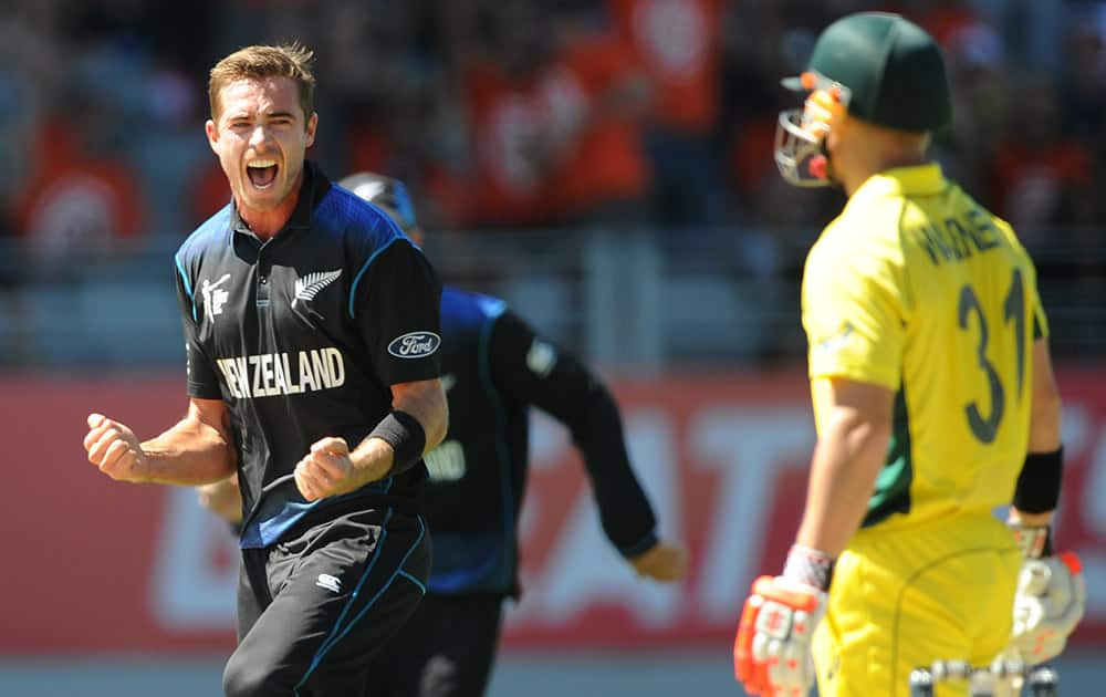 New Zealand's Tim Southee celebrates after taking the wicket of Australia's David Warner, right, during their Cricket World Cup match in Auckland, New Zealand.