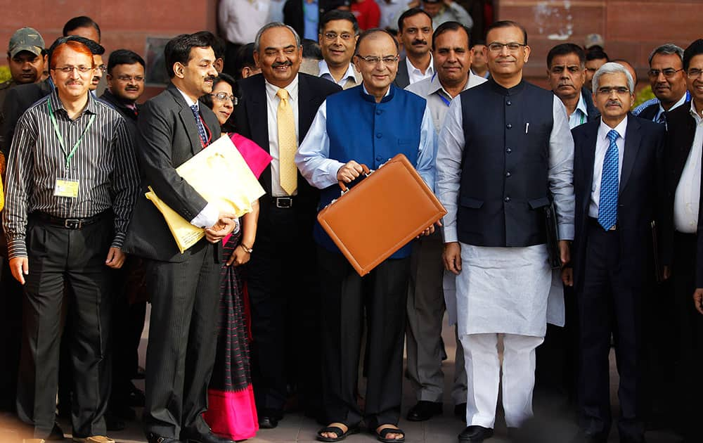 Finance Minister Arun Jaitley, center in blue jacket, display a briefcase containing union budget for the year 2015-16 as he leaves his office for Parliament to present the union budget in New Delhi, India.