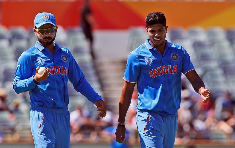 Virat Kohli left, looks at the ball as he walks next to bowler Umesh Yadav during their Cricket World Cup Pool B match against the United Arab Emirates in Perth, Australia.