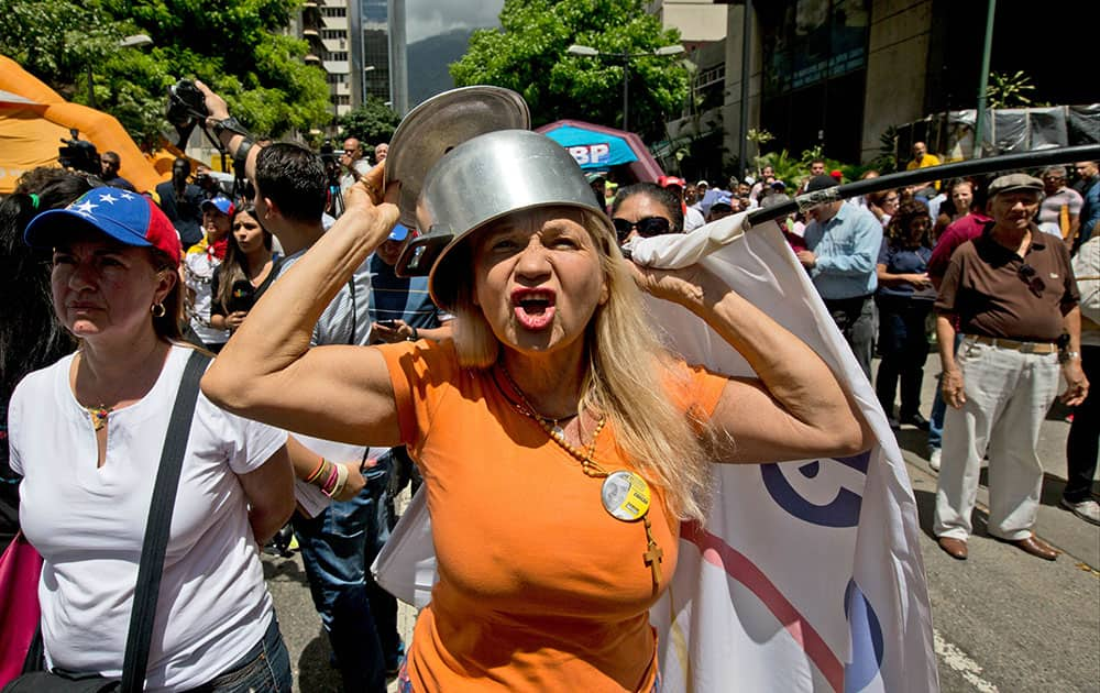 An opposition member wearing a pot on her head shouts slogans against Venezuela's President Nicolas Maduro during a protest in Caracas, Venezuela.