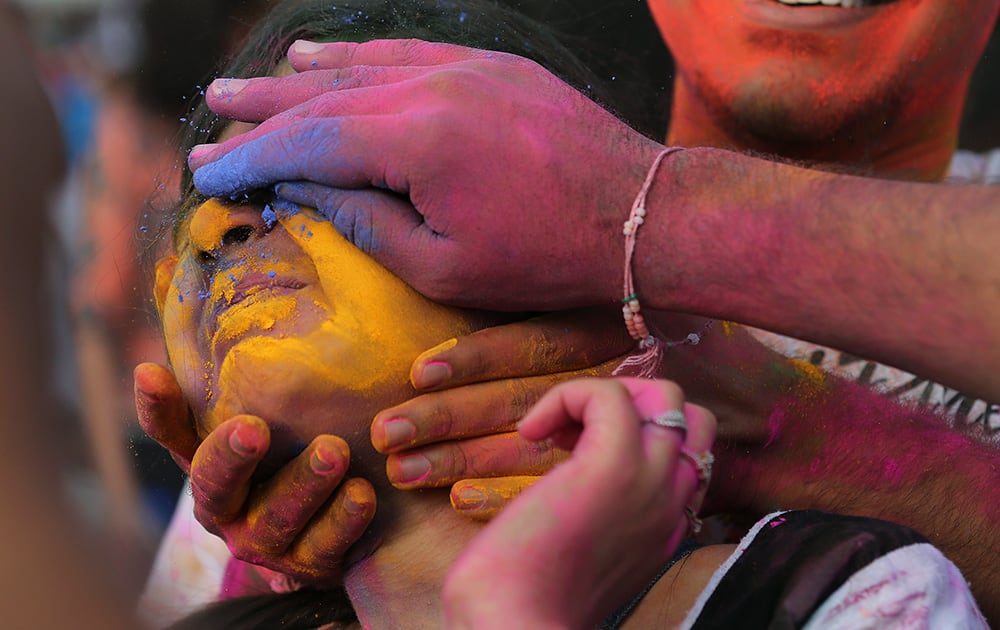 Participants place colored powder on a woman's face as they join celebrations of the Holi festival in suburban Pasay, south of Manila, Philippines.