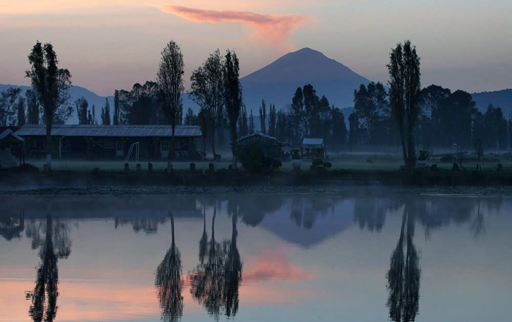 The Popocatepetl volcano spews ash and steam, seen from the water canals of Xochimilco, as the sun rises in Mexico City.