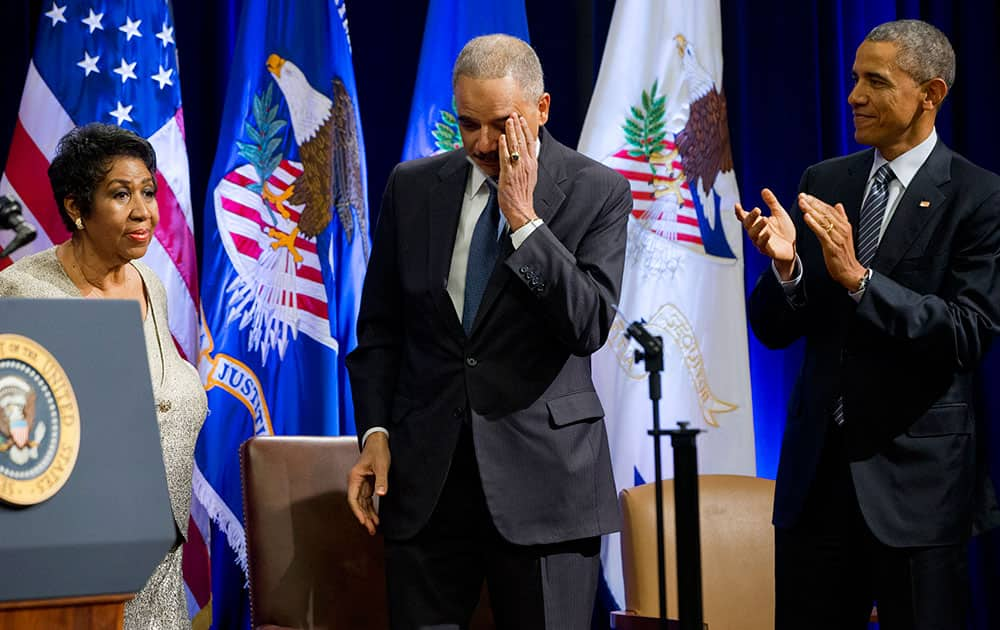 An emotional outgoing Attorney General Eric Holder, center, reacts after singer Aretha Franklin, left, finished singing a song for him, next to President Barack Obama, at an event celebrating Holder at the Department of Justice in Washington.