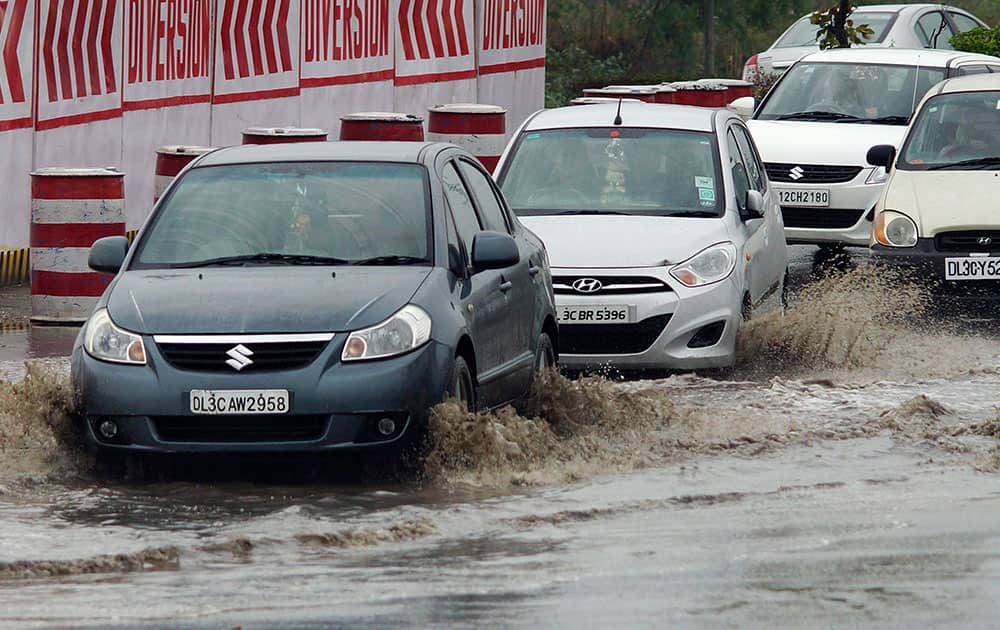 Cars move in a waterlogged street during rains in New Delhi.
