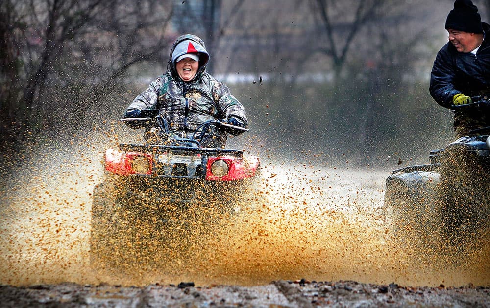 While much of Memphis stayed indoors out of the drizzling cold rain, Vallorie Higgins, left, and Omar Tellez take advantage of the wet day to fly through mud holes along Covington Pike near the Wolf River in Memphis, Tenn.