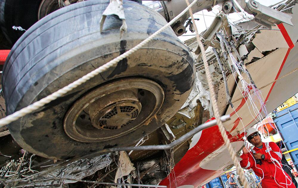 A crew member stands near the newly-recovered remains of the fuselage of the ill-fated AirAsia Flight 8501 on the deck of rescue ship Crest Onyx at Tanjung Priok port in Jakarta, Indonesia.